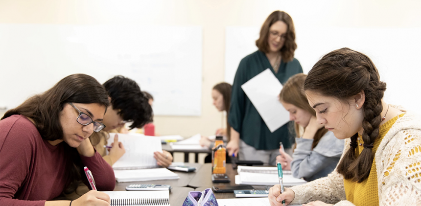 A teacher walking by some students working on some calculus problems